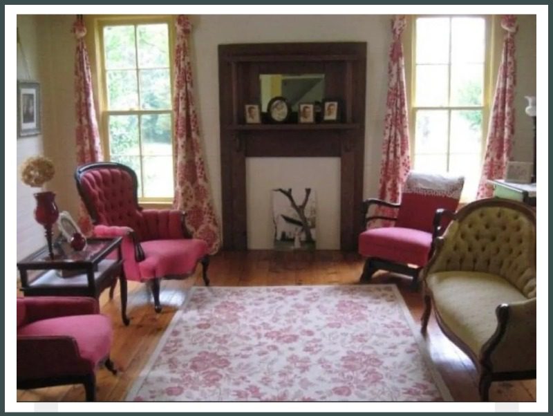 A living room with pink chairs and a fireplace.