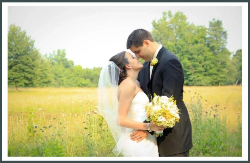 A bride and groom kissing in the middle of a field.